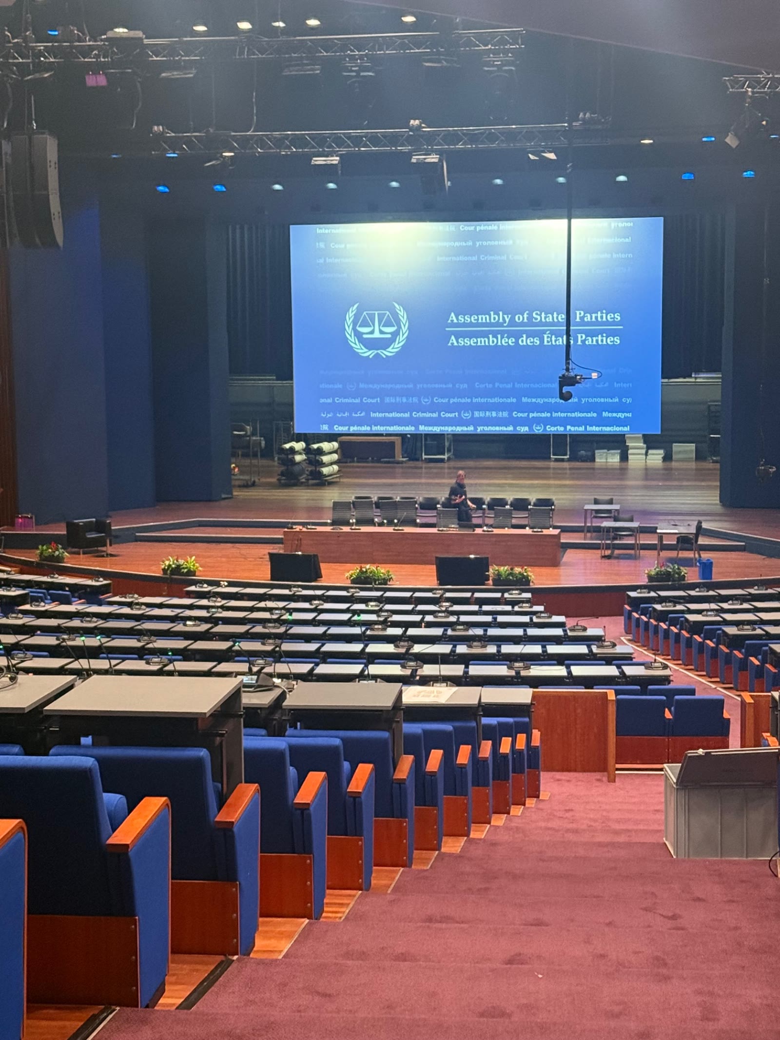 Congreszaal met vergadertafels en groot podiumscherm klaar voor een internationale conferentie