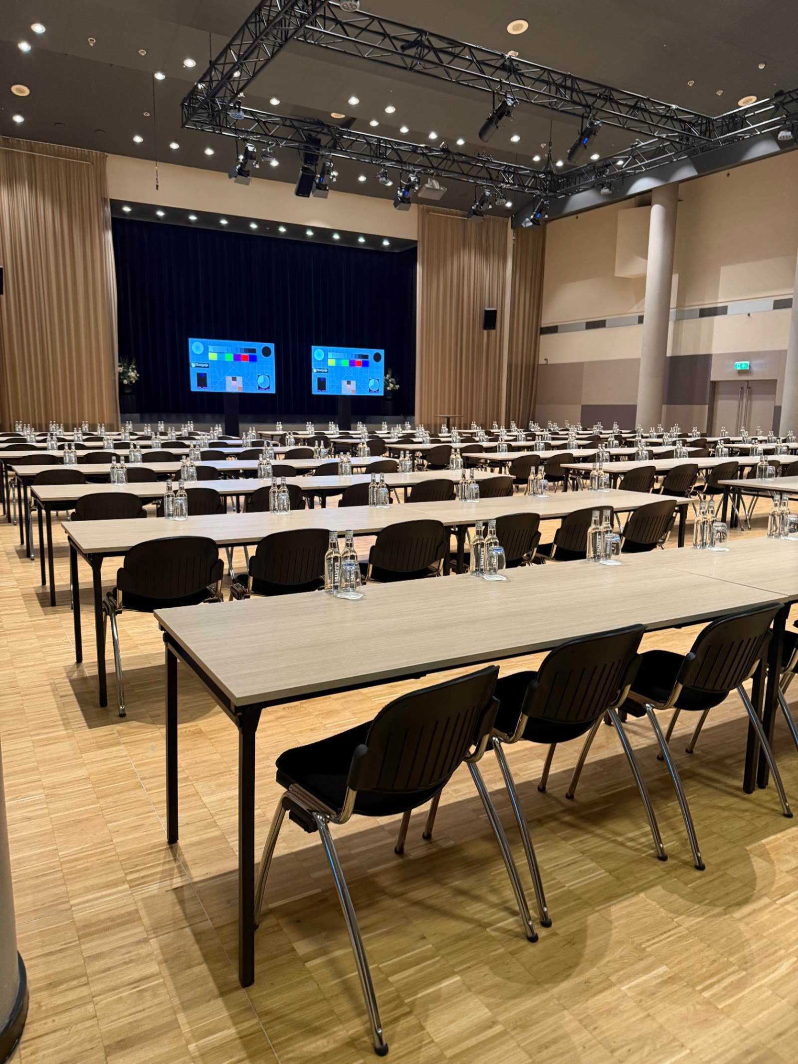 Zaal met lange tafelrijen en stoelen in schoolopstelling klaar voor een congres