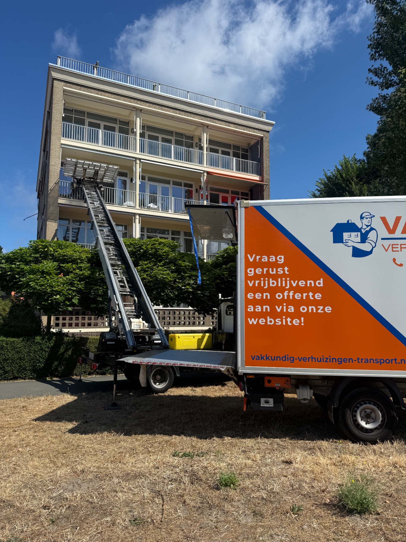 Bakwagen van Vakkundig met uitgeschoven verhuislift naar een balkon