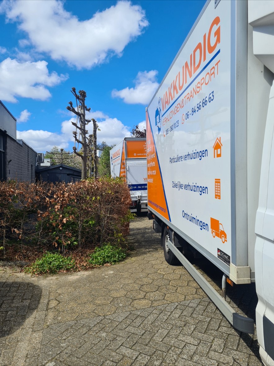Twee verhuiswagens van Vakkundig achter een bedrijfspand