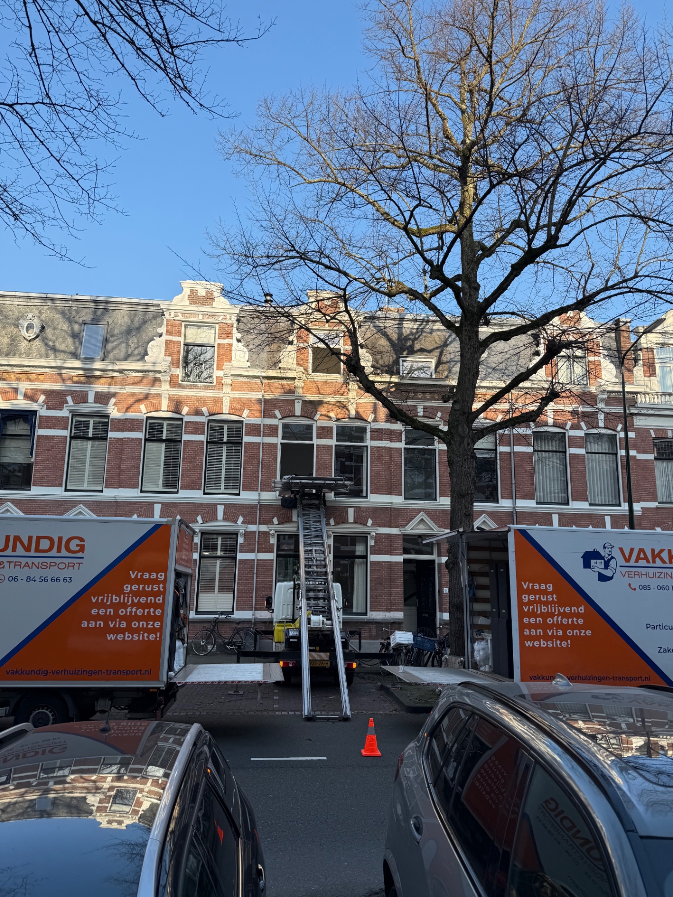 Twee verhuiswagens en een verhuislift voor een herenhuis tijdens een woningverhuizing