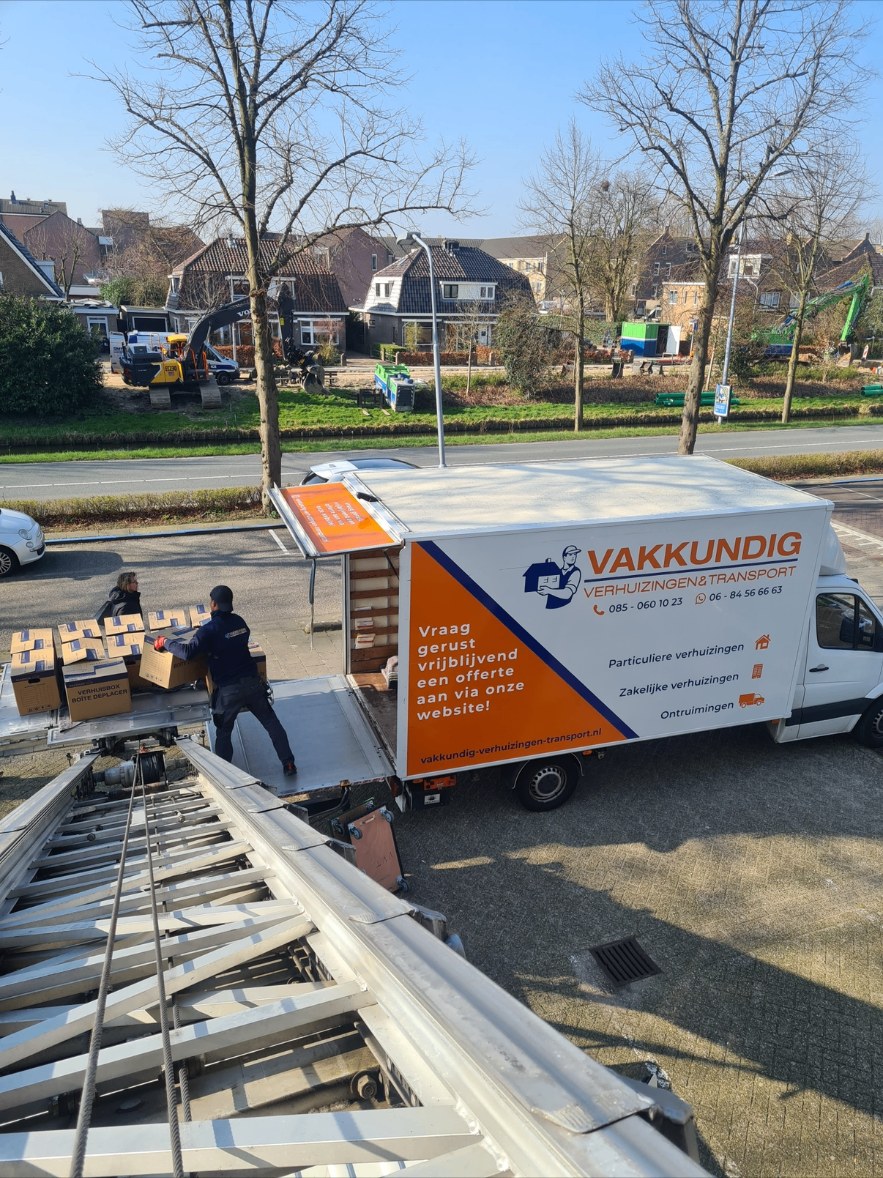Verhuizer laadt verhuisdozen in de bakwagen via de verhuislift